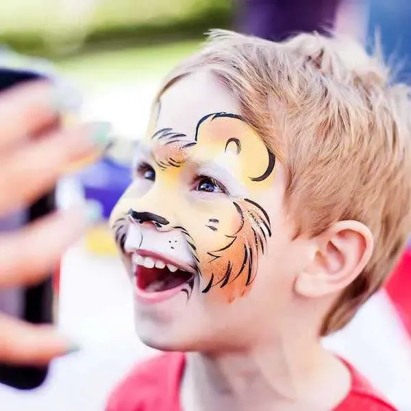 A laughing boy with lion face paint at a kids party