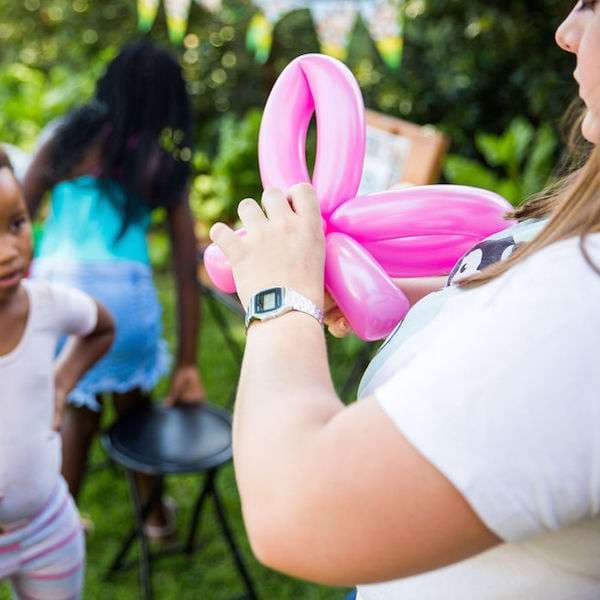 A balloon twister entertaining a group of kids with colorful balloon creations