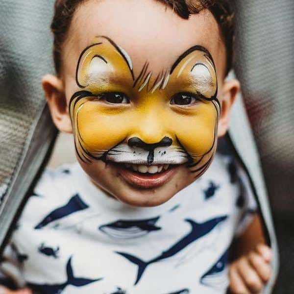 A face painter carefully painting a design on a child's cheek at a party