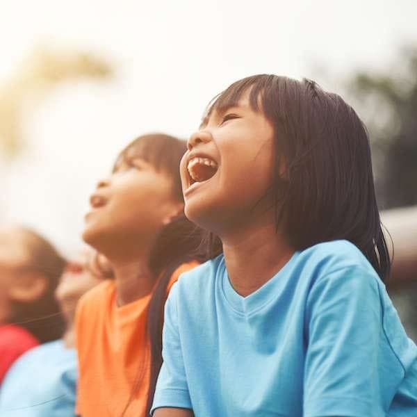 A crowd of kids laughing in delight during a magic show